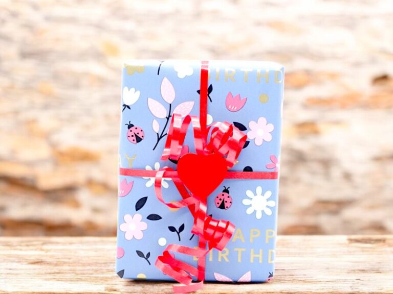 Geburtstagsgeschenk mit rotem Herz-Clip auf blauem Geschenkpapier